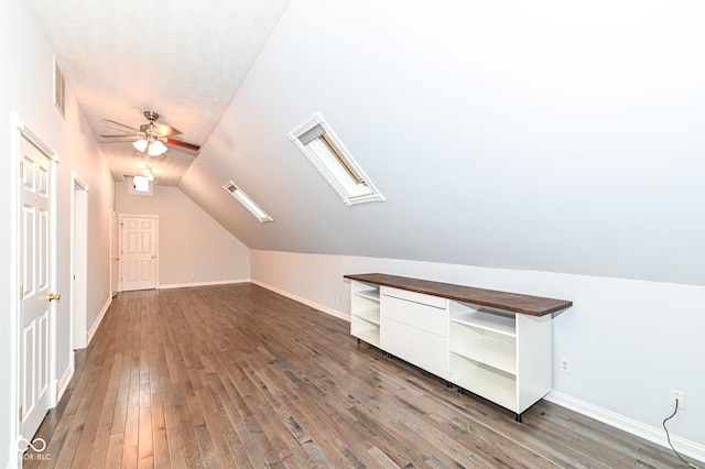 additional living space featuring dark wood-type flooring, ceiling fan, and lofted ceiling with skylight