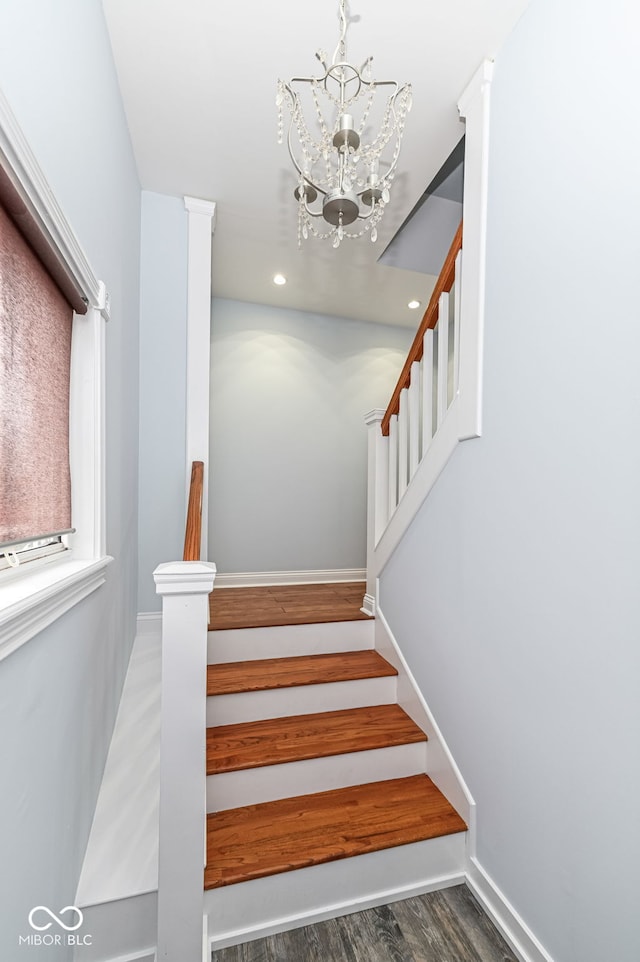 stairway featuring hardwood / wood-style floors and a chandelier