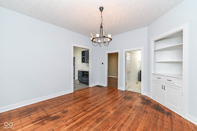 unfurnished dining area featuring an inviting chandelier, dark hardwood / wood-style flooring, and a textured ceiling