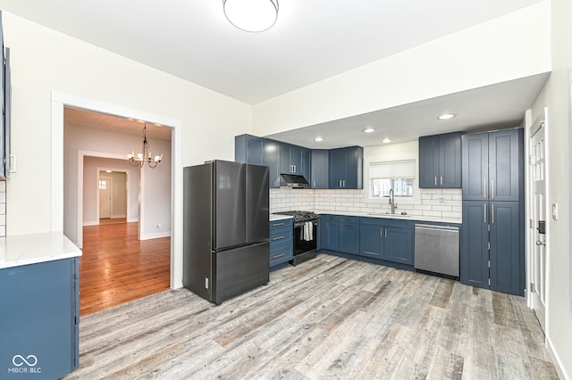 kitchen with blue cabinets, sink, stainless steel appliances, light hardwood / wood-style floors, and decorative backsplash