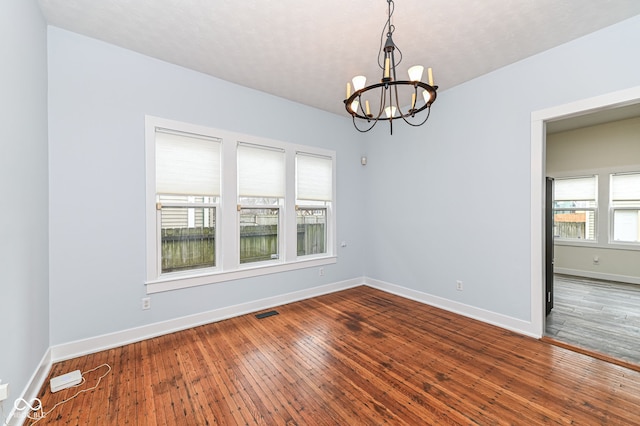 empty room featuring wood-type flooring and a chandelier