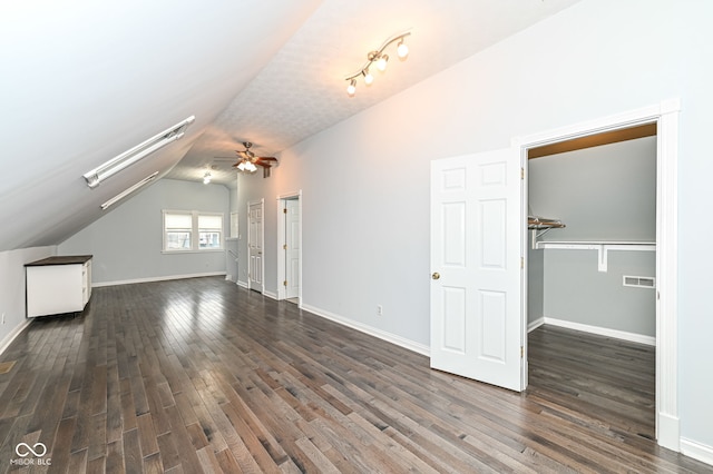 additional living space with dark wood-type flooring, lofted ceiling with skylight, and ceiling fan