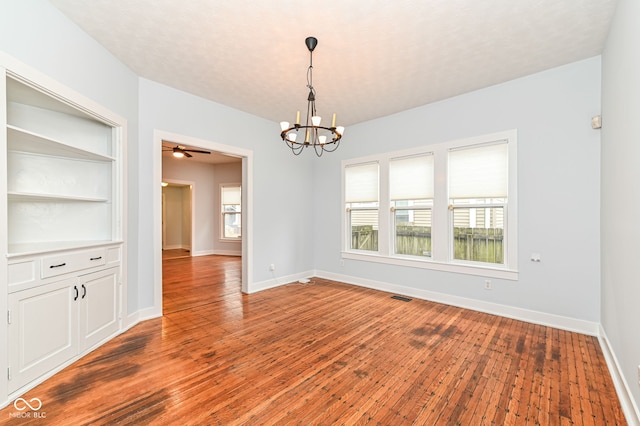 empty room featuring ceiling fan with notable chandelier and wood-type flooring