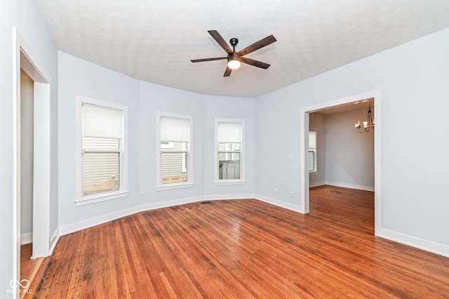 empty room featuring ceiling fan with notable chandelier and hardwood / wood-style floors