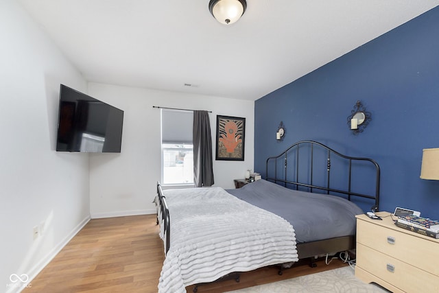 bedroom with light wood-type flooring and baseboards