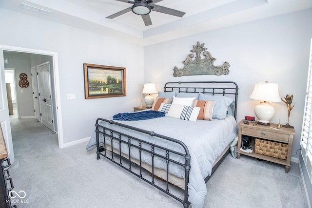 bedroom featuring ceiling fan, a raised ceiling, and light carpet