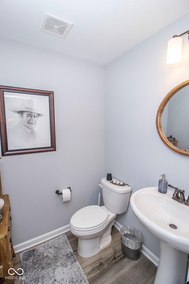 bathroom featuring toilet and wood-type flooring