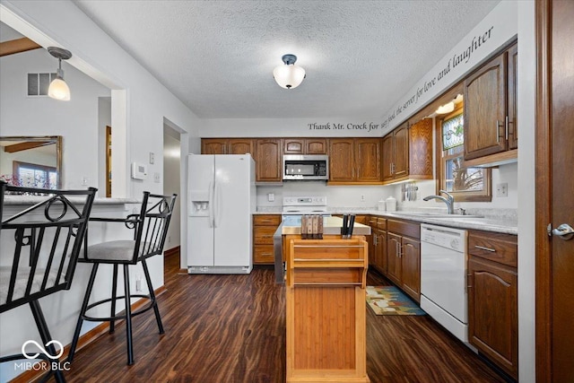 kitchen featuring white appliances, dark wood-style flooring, a sink, visible vents, and light countertops