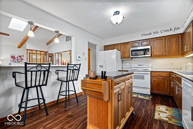 kitchen featuring white appliances, a skylight, visible vents, brown cabinetry, and dark wood-style floors