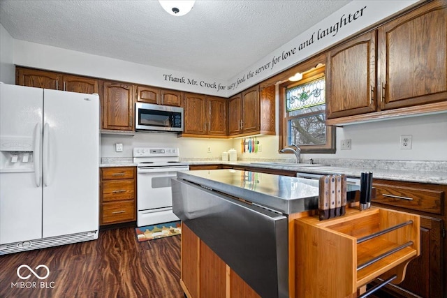 kitchen featuring dark wood-style floors, light countertops, white appliances, and a textured ceiling