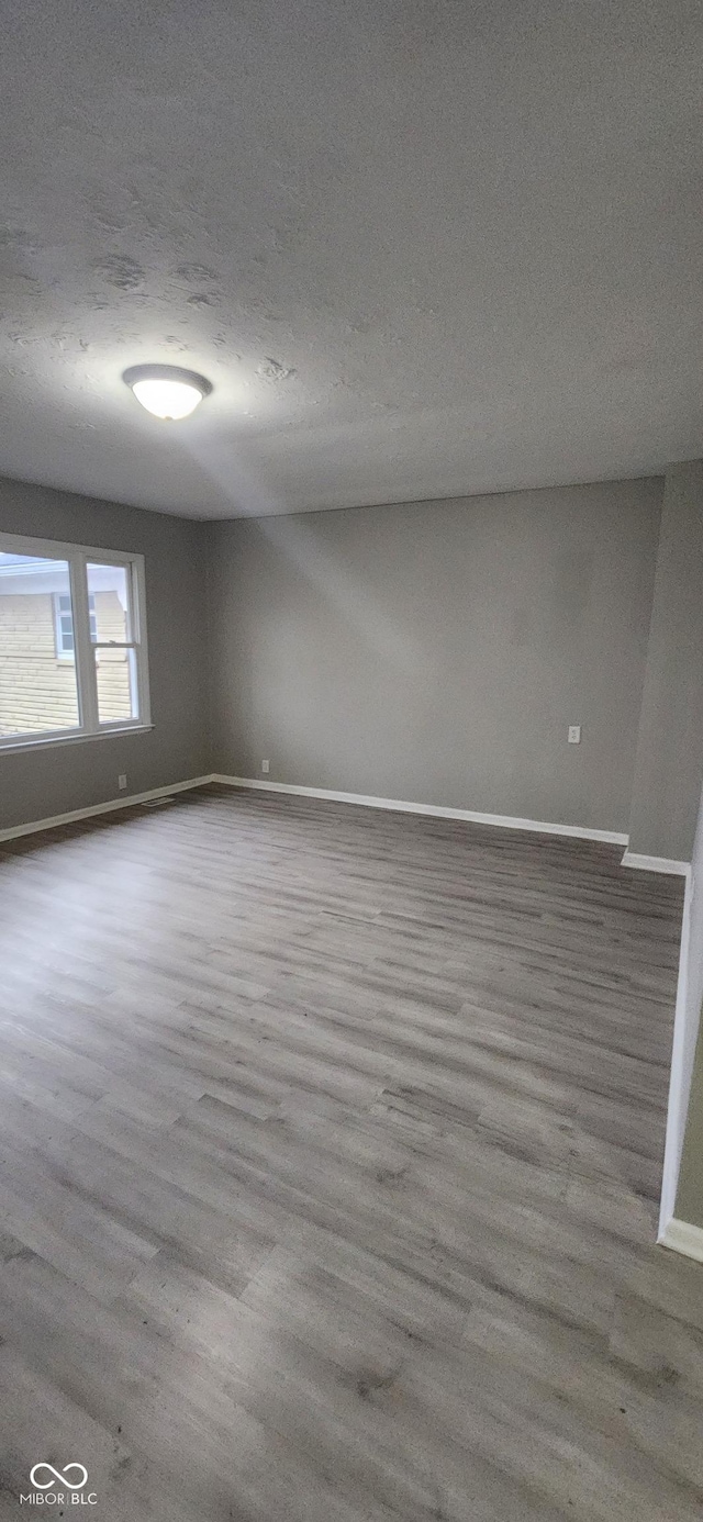 spare room with a textured ceiling and light hardwood / wood-style flooring