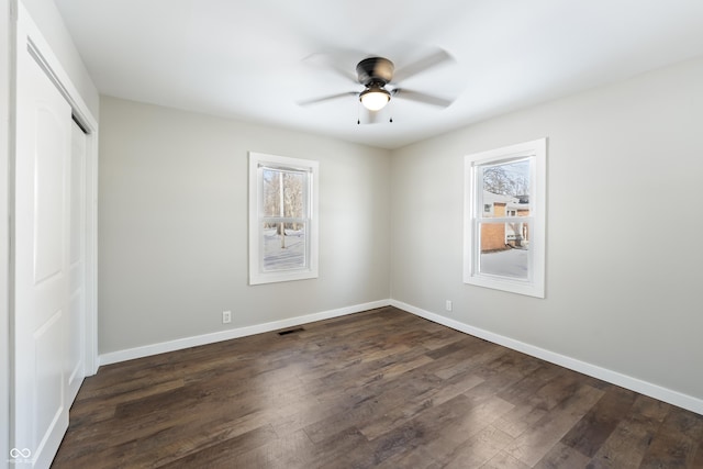 unfurnished bedroom featuring ceiling fan, a closet, and dark wood-type flooring