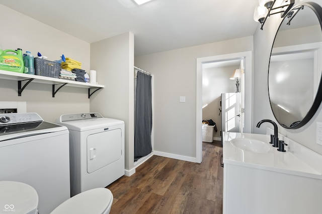 clothes washing area with washing machine and dryer, sink, and dark hardwood / wood-style floors