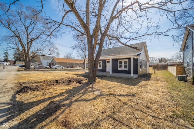 view of front of property featuring cooling unit, a shingled roof, and fence