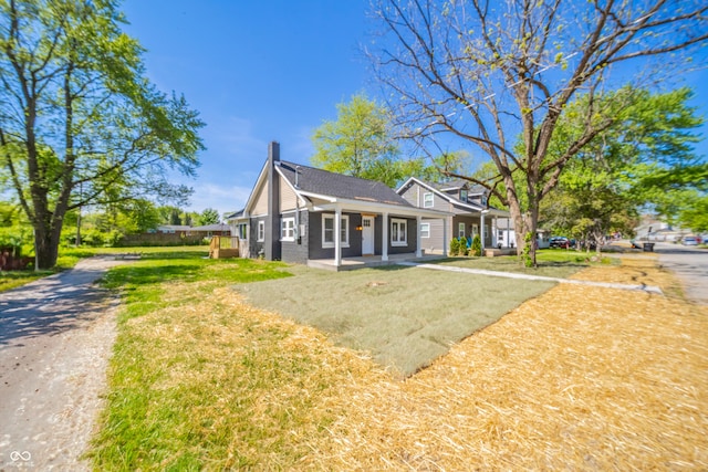 227 W 7th St, Lapel, IN 46051 - view of front of house with covered porch, a chimney, a front lawn, and dirt driveway