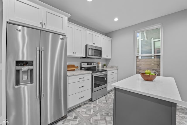 kitchen featuring light stone countertops, white cabinetry, appliances with stainless steel finishes, and a kitchen island