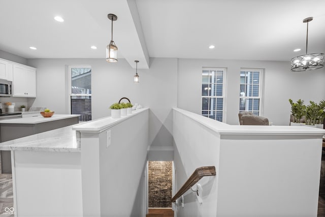 interior space with a healthy amount of sunlight, hanging light fixtures, stainless steel appliances, and white cabinets