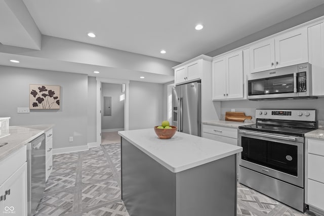 kitchen with white cabinetry, light stone counters, a center island, appliances with stainless steel finishes, and electric panel