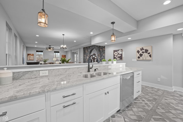 kitchen with sink, light stone counters, white cabinets, decorative light fixtures, and stainless steel dishwasher