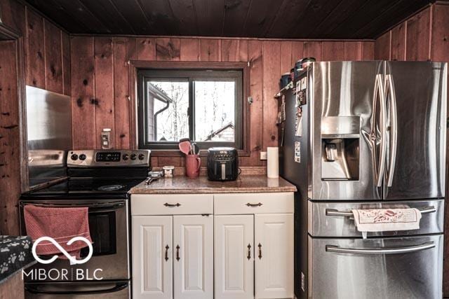 kitchen featuring white cabinetry, wood ceiling, stainless steel appliances, and wood walls