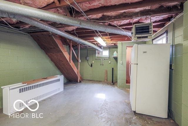 basement with white refrigerator and radiator heating unit