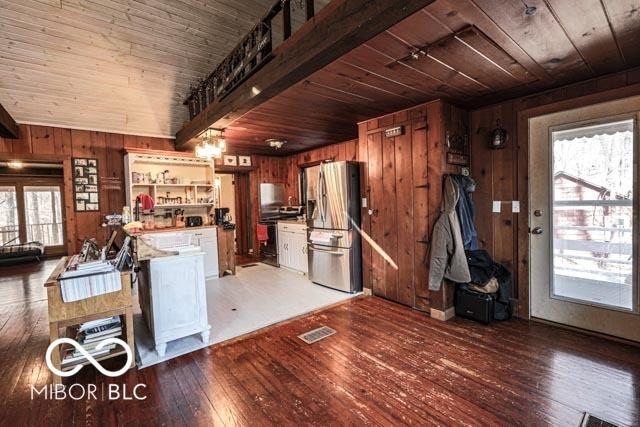 kitchen featuring stainless steel fridge with ice dispenser, wooden walls, and wooden ceiling