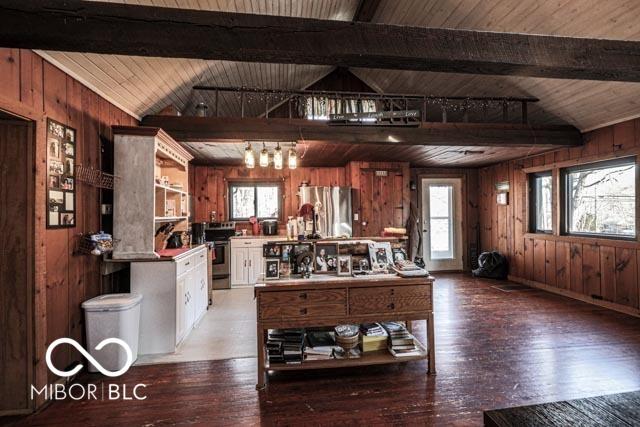 kitchen featuring hardwood / wood-style flooring, stainless steel appliances, white cabinets, and wood walls