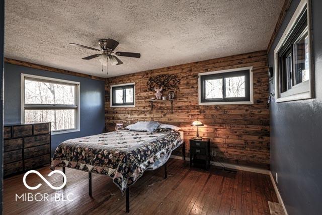 bedroom with wood-type flooring, ceiling fan, and a textured ceiling