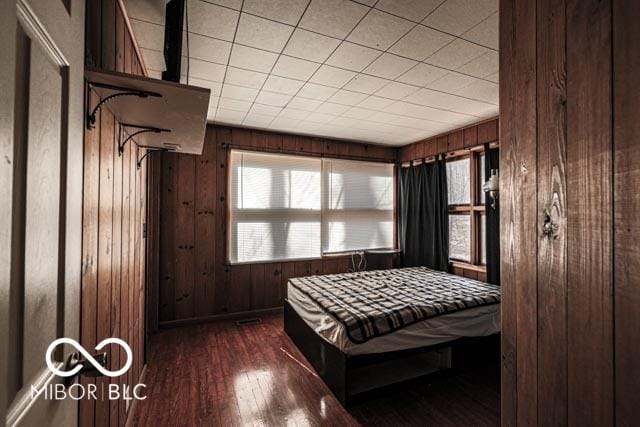 bedroom with dark hardwood / wood-style floors and wood walls