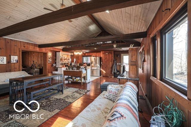 living room featuring vaulted ceiling with beams, hardwood / wood-style floors, wooden ceiling, and wood walls