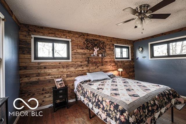 bedroom featuring multiple windows, ceiling fan, hardwood / wood-style floors, and a textured ceiling