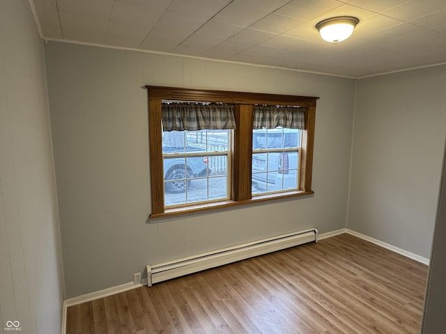 spare room featuring baseboard heating and wood-type flooring