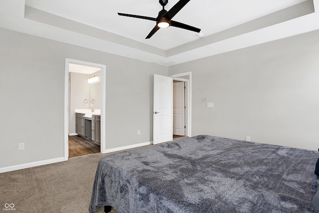 bedroom with baseboards, ceiling fan, dark carpet, and a raised ceiling