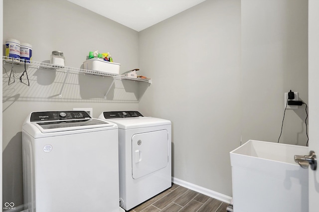 washroom featuring laundry area, wood finish floors, a sink, separate washer and dryer, and baseboards