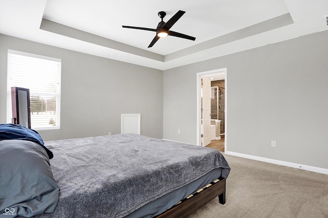 bedroom with a ceiling fan, a tray ceiling, light carpet, and baseboards