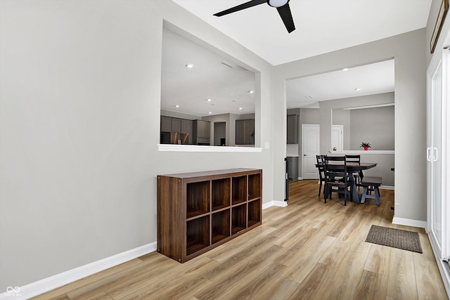 interior space featuring a ceiling fan, baseboards, and light wood finished floors