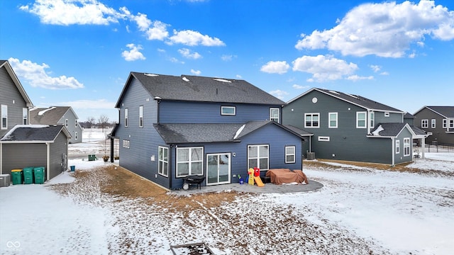 snow covered property with a shingled roof and a residential view