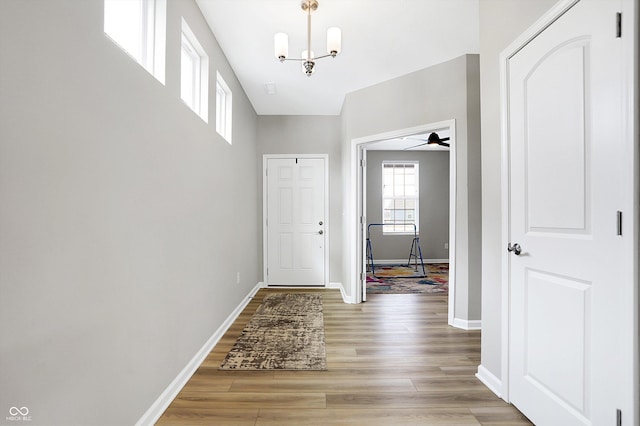 interior space featuring light wood-type flooring, baseboards, and a notable chandelier