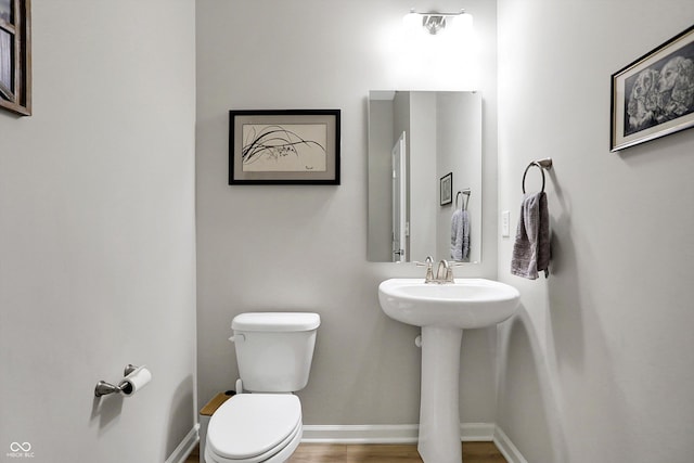 bathroom featuring a sink, baseboards, toilet, and wood finished floors