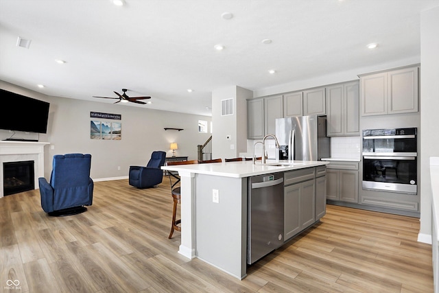 kitchen featuring a sink, gray cabinets, stainless steel appliances, open floor plan, and a ceiling fan