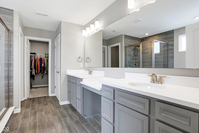 full bath featuring a sink, a shower stall, double vanity, and a spacious closet