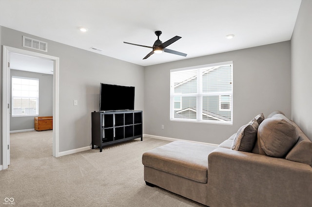living room featuring baseboards, a ceiling fan, light colored carpet, and visible vents