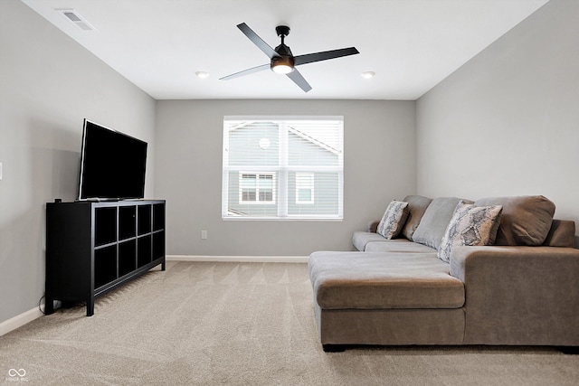 living room with baseboards, ceiling fan, visible vents, and light carpet