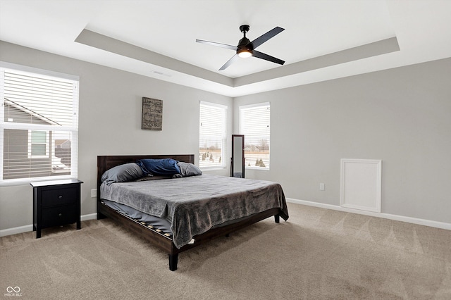 bedroom featuring a tray ceiling, visible vents, light carpet, and baseboards
