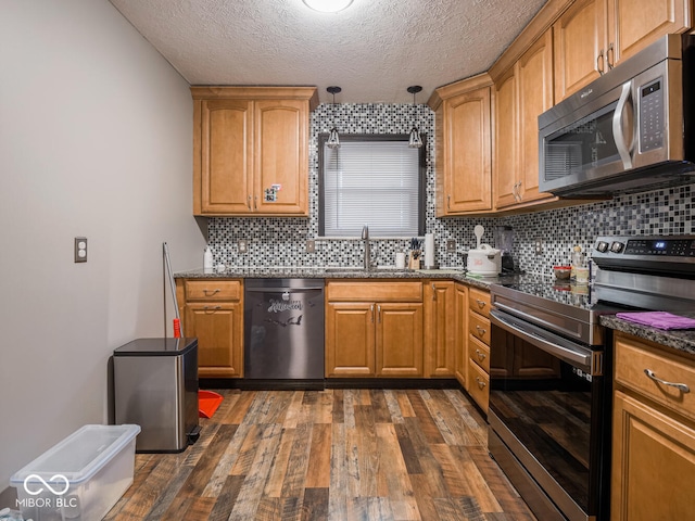 kitchen featuring decorative light fixtures, tasteful backsplash, sink, stainless steel appliances, and dark wood-type flooring