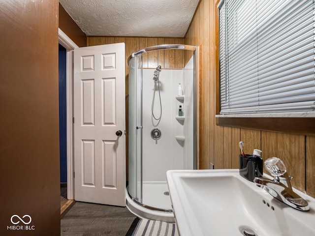 bathroom featuring sink, a textured ceiling, wooden walls, and walk in shower