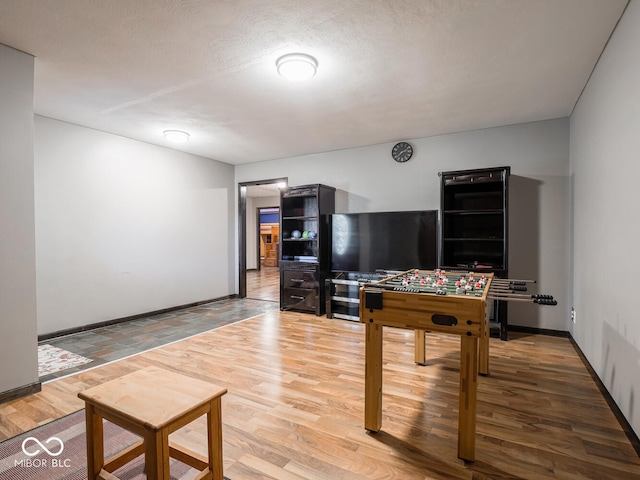 game room featuring wood-type flooring and a textured ceiling