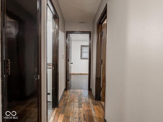 hallway featuring dark wood-type flooring and a textured ceiling