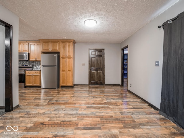 kitchen featuring hardwood / wood-style flooring, appliances with stainless steel finishes, a textured ceiling, and decorative backsplash