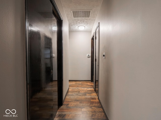 hallway featuring dark hardwood / wood-style flooring and a textured ceiling